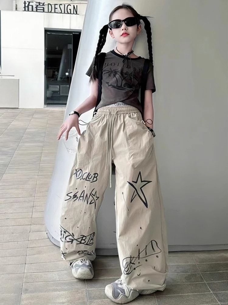 女の子のクールな格好のスーツ2025新型の夏の女の子の不規則な半袖のtシャツの子供のストレートなズボンの揚げ物の2つのセット