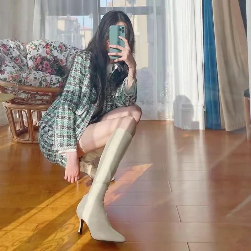 はらはらとした白い長靴の女性の新型ハイヒールがやせているブーツの騎士靴の先が膝を越えて冬になる