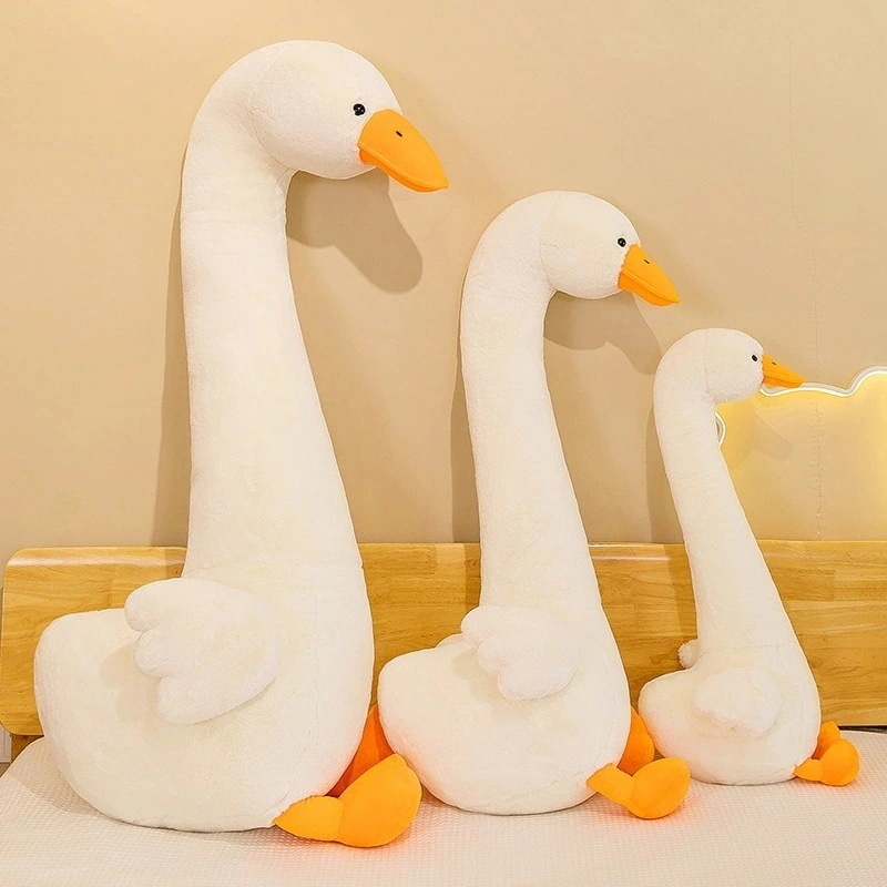 首の長い恐竜ビッグガチョウのぬいぐるみ人形をベッドの上に置き女の子が足と枕で快適に眠ることができますおもちゃの人形