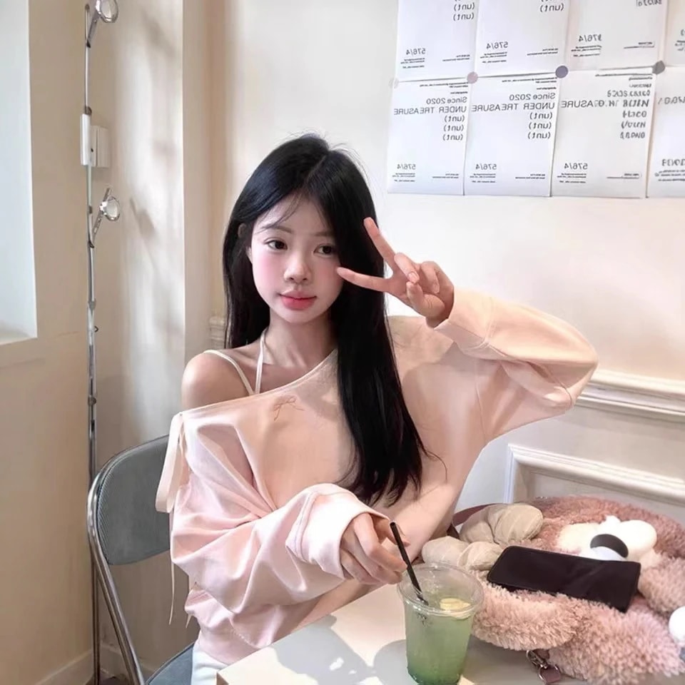 ピンクのゆったりとしたオフショルダーのレディース スウェットシャツ春と秋に 小柄な女性向け甘くてゆったりとしたフィット感刺繍入りのリボンラウンドネック長袖