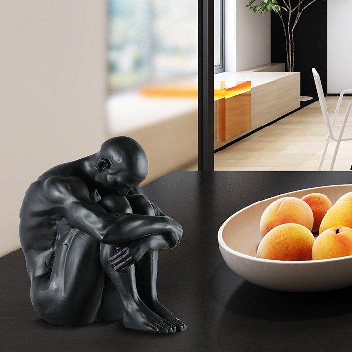 膝を抱えて座る人の置物