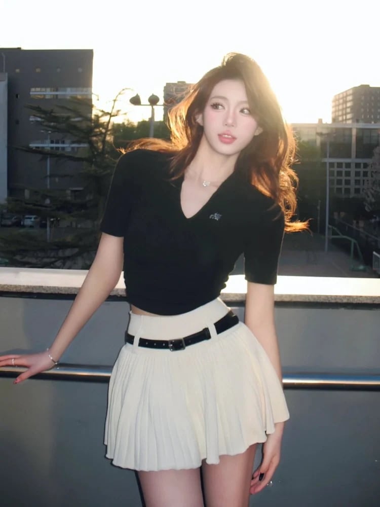 黒の半袖トップスプリーツニットショートスカートツーピーススーツを着た軽くてな雰囲気の女性