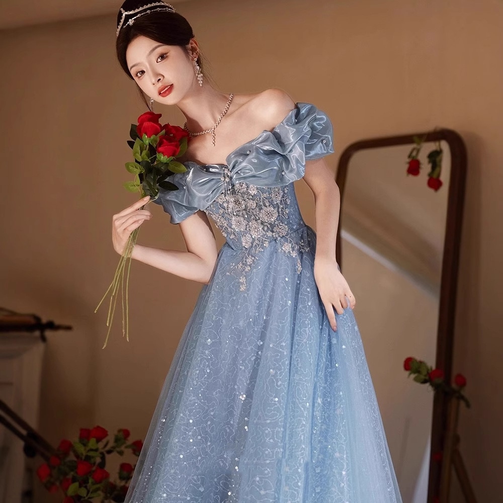 オフショルダーの青いイブニングドレス2026 年の女性プレゼンターとしては驚くほど美しく洗練されています