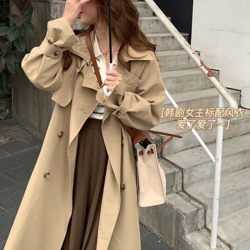 雰囲気のあるトレンチコートの女性は秋にとしたダブルボタンの小柄な中長タイプのコートを着て新しい服を着ています