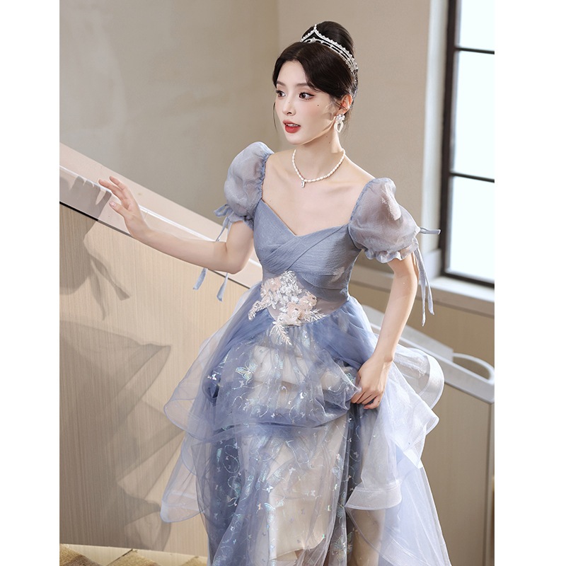 青いドレスのスカートの女性は贅沢で高級な年次総会の司会者の声楽芸は成人式の高級感のある宴会を受験した