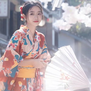 日本の女性の着物の新モデル赤い着物の桜の花の桜の鶴の着物の花のプリントの復古の改良旅は写真の服装を撮ります